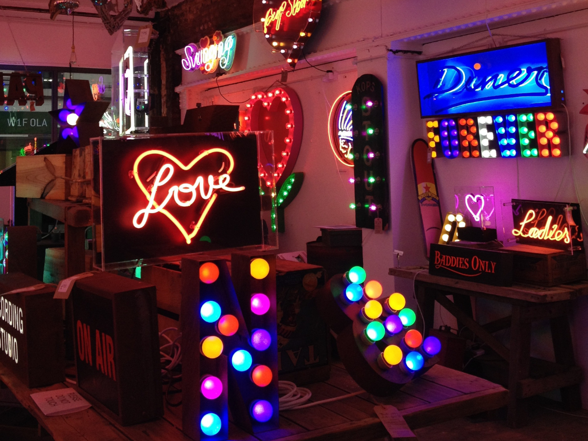 Neon signs at God's Own Junkyard in central London. Neons include 'Love', 'Ladies', 'Diner' and 'Baddies only'.