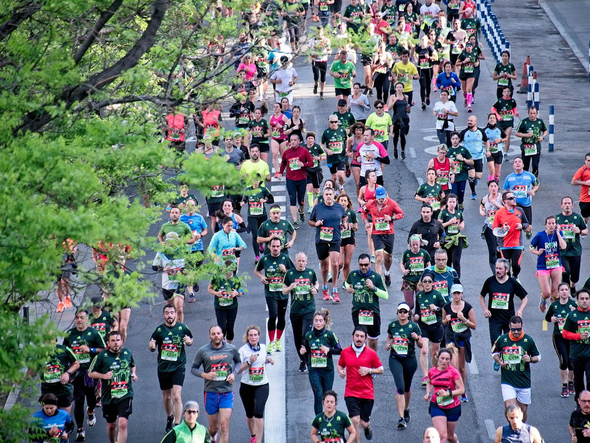 A group of marathon runners are photographed from above. They are running on tarmac.