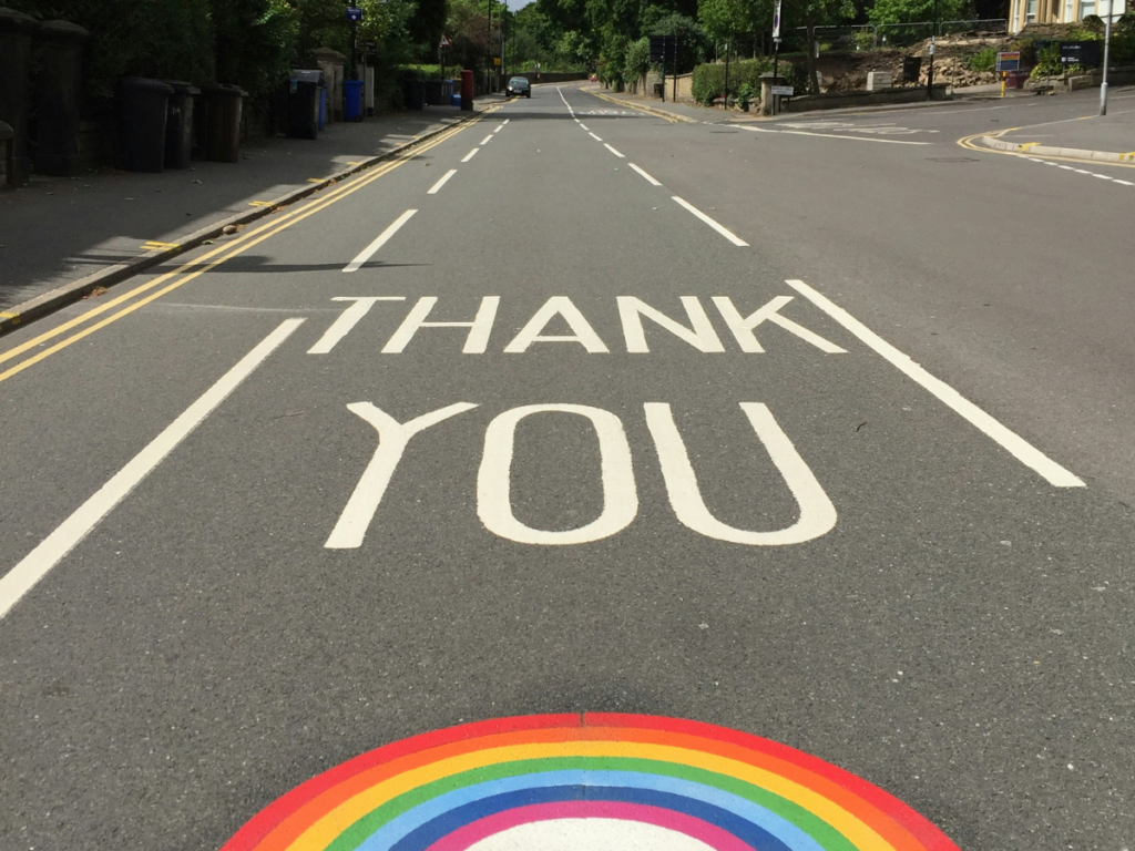 A tarmac road in the UK is painted with 'thank you' and a rainbow.