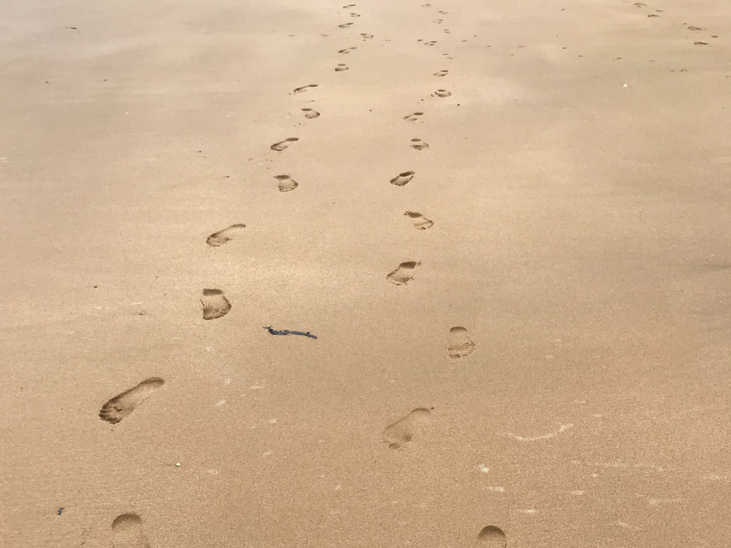 10 steps to a healthier you 1 Two pairs of barefoot prints in the sand along a clear sandy beach. One set is larger than the other.