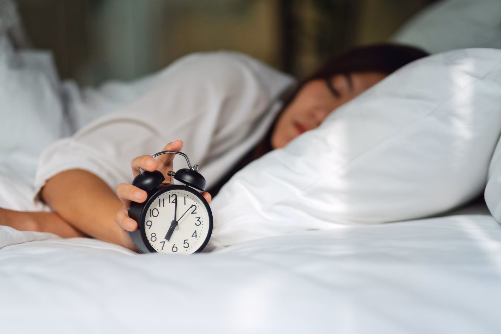 an asian woman turning off an alarm clock while sl 2026 01 07 06 38 15 utc converted